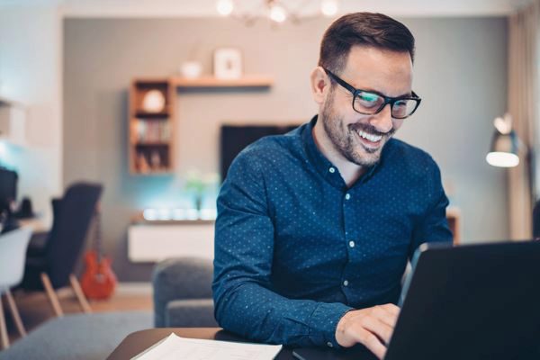 man smiling while he works at his computer 