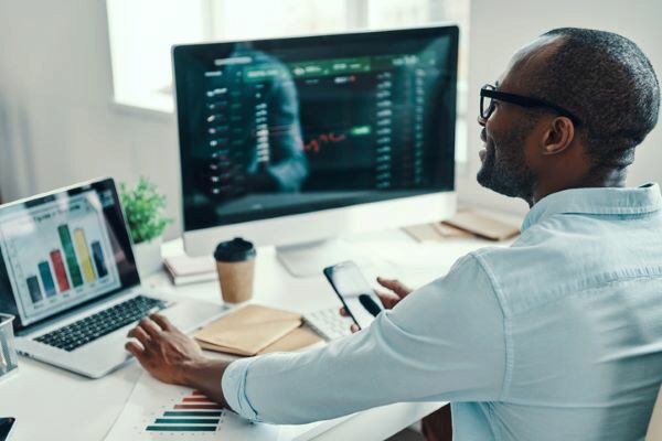 man sits at desk and looks at investments