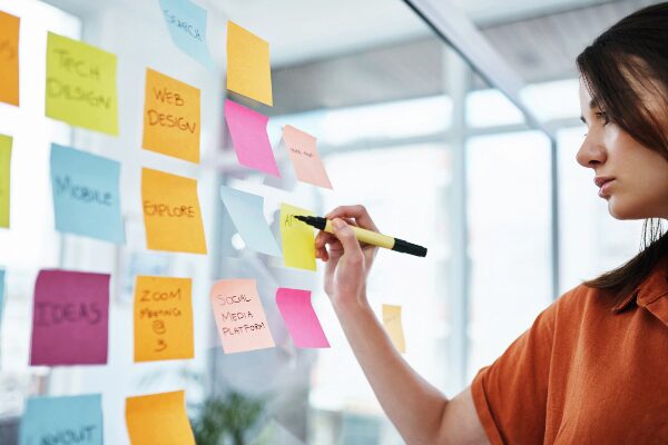 Young businesswoman brainstorming digital marketing ideas on multicolored notecards