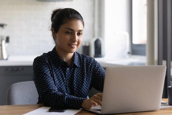 Young woman writing resume on laptop