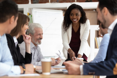 Female leading a team meeting at a table.