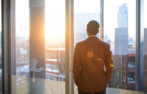 Businessman looking through office window in sunlight