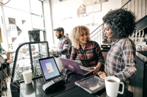 Two coffee shop owners using mobile payment technology