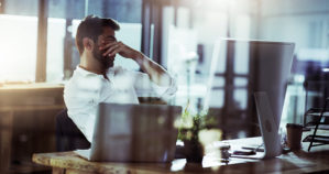 Picture of a young businessman looking stressed while working late in the office