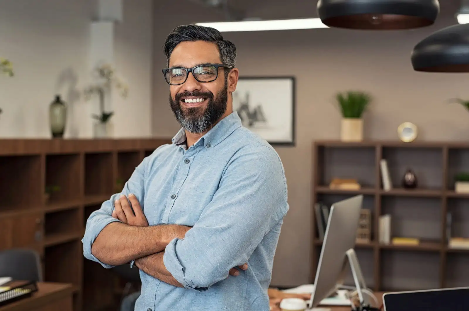 professional man smiling in his office with arms crossed